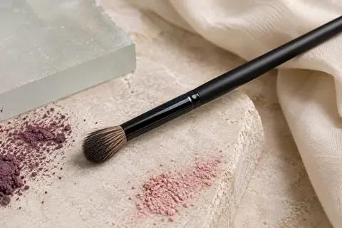 Pinceau estompeur Beter noir à poils naturels posé sur une pierre claire près de pigments poudrés.