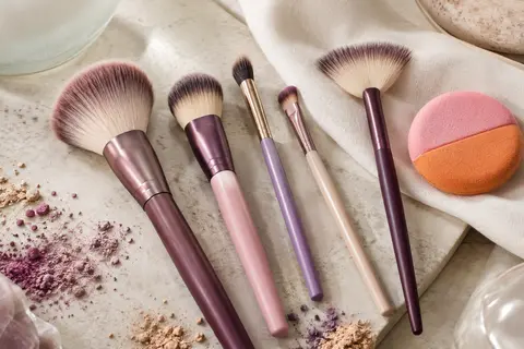 Cinq pinceaux de maquillage multicolores et une houppette double face rose et orange