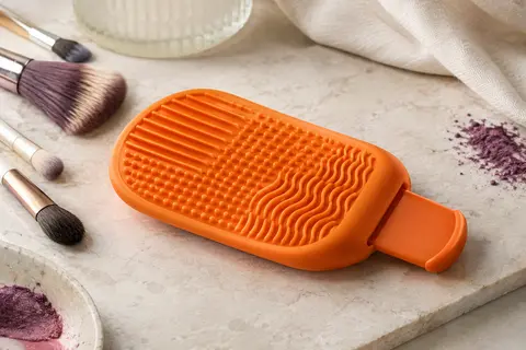 Palette de nettoyage orange en silicone avec poignée rétractable et rainures texturées pour pinceaux